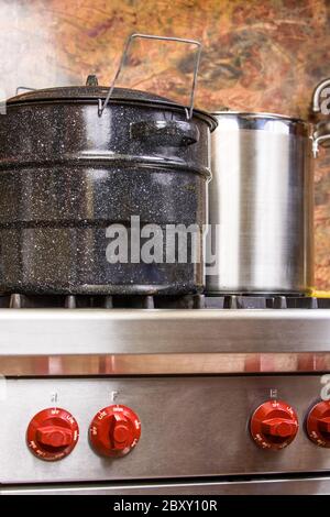 bollitore per inscatolamento blu e grande pentola di brodo in acciaio inossidabile che viene utilizzato per preparare la marmellata di albicocche su una stufa di alta qualità Foto Stock