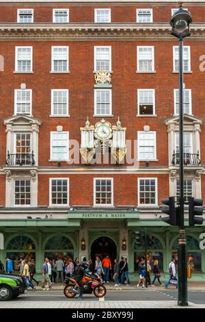 La facciata e l'entrata trafficata al grande magazzino Fortnum & Mason in Piccadilly Street a Londra Foto Stock