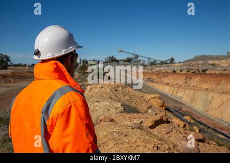 Minatore non identificabile di fronte a una strada porticata per le miniere di rame, con minehead in background nel NSW Australia Foto Stock