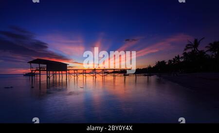 Incredibile splendido tramonto con silhouette di legno e albero di cocco a Mantanani Island, Sabah, Borneo. L'isola di Mantanani ha un lungo tratto di bianco Foto Stock