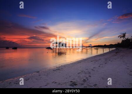 Incredibile splendido tramonto con silhouette di legno e albero di cocco a Mantanani Island, Sabah, Borneo. L'isola di Mantanani ha un lungo tratto di bianco Foto Stock