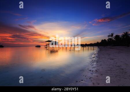 Incredibile splendido tramonto con silhouette di legno e albero di cocco a Mantanani Island, Sabah, Borneo. L'isola di Mantanani ha un lungo tratto di bianco Foto Stock