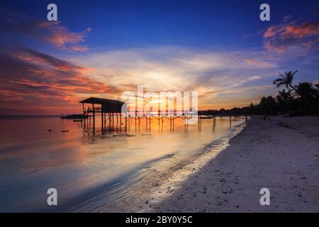 Incredibile splendido tramonto con silhouette di legno e albero di cocco a Mantanani Island, Sabah, Borneo. L'isola di Mantanani ha un lungo tratto di bianco Foto Stock