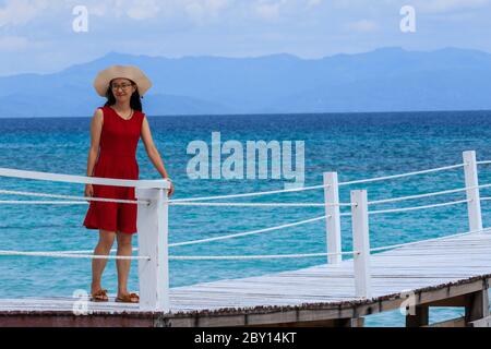 Isola di Mantanani, Sabah, Malesia-CIRCA SETTEMBRE, 2017:giovani donne asiatiche in rosso che si divertono al molo di legno all'isola di Mantanani, Kota Belud, Sabah, Foto Stock