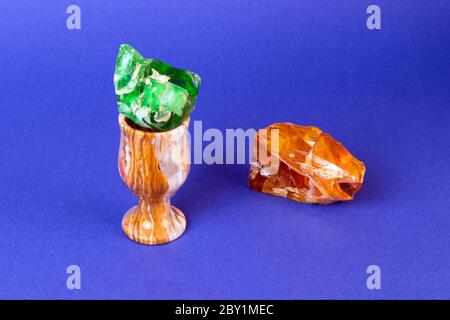 Piccolo ed elegante vetro onice con gemma verde all'interno e pezzo di ambra grezzo isolato su sfondo viola Foto Stock