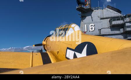 Giallo T 6 Texan addestramento aereo di sostegno sul ponte di volo della portante dell'aeromobile dell'era WW2 Lexington in Texas con torre di controllo sullo sfondo. Foto Stock