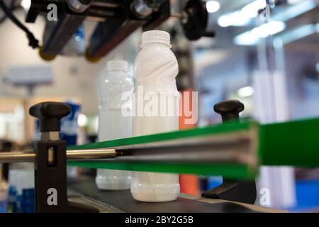 Bottiglie di latte bianche su una linea di produzione in un caseificio. Foto Stock