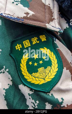 Emblema della polizia armata del popolo cinese sopra i fati dell'esercito camuffato Foto Stock