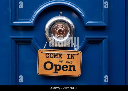 Ristorante 'Open' cartello in legno appeso su una porta blu. Foto Stock