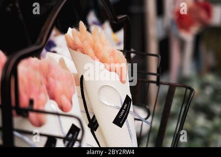 Piccoli mini bouquet di fiori rosa avvolti con carta su un ripiano nero. Foto Stock