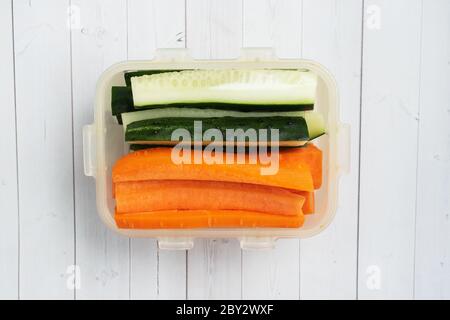 Bastoncini di carote e cetrioli freschi in un contenitore. Misurazione centimetrica del volume. Concetto di alimentazione dietetica. Spazio di copia Foto Stock