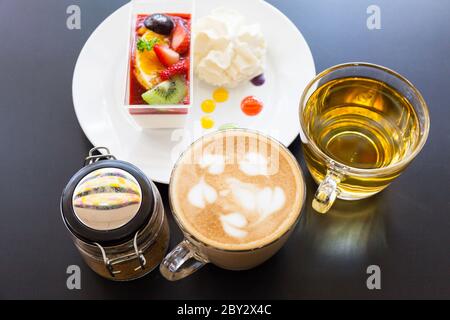 crema di fragole e una tazza di tè e caffè su sfondo di legno, fuoco selettivo Foto Stock