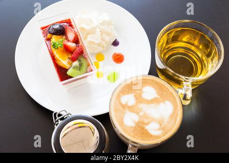 crema di fragole e una tazza di tè e caffè su sfondo di legno, fuoco selettivo Foto Stock