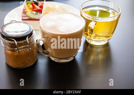 crema di fragole e una tazza di tè e caffè su sfondo di legno, fuoco selettivo Foto Stock