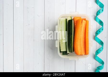 Bastoncini di carote e cetrioli freschi in un contenitore. Misurazione centimetrica del volume. Concetto di alimentazione dietetica. Spazio di copia Foto Stock