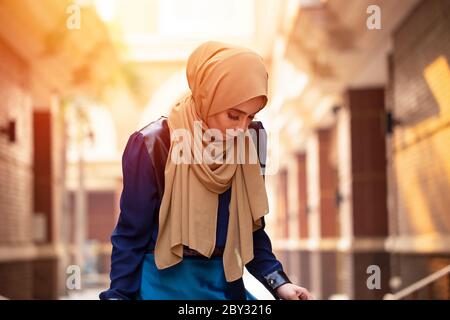 Ritratto di giovane musulmana asiatica che indossa sciarpa testa hijab in città. Closeup faccia allegra donna coperta con foulard all'aperto Foto Stock