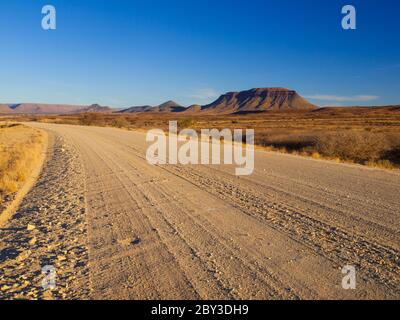 Strada ghiaiosa e montagna tabella nel sud della Namibia Foto Stock