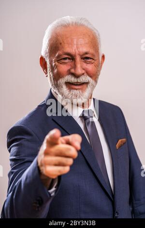 Ritratto di felice uomo d'affari senior che punta a voi. Foto Stock