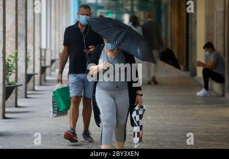 Palma, Spagna. 8 giugno 2020. Passers-by passeggiata lungo una strada in tempo piovoso con i boccagli di guardia. Dal 08.06.2020, nella 'fase 3' del relax delle misure corona, i negozi potranno far entrare più persone, sarà possibile consumare nei ristoranti e presso i banconi, tra gli altri. Credit: Clara Margais/dpa/Alamy Live News Foto Stock