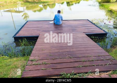 Bangkok, Thailandia - 25 maggio 2020 : uomo di nome non identificato seduto sul molo di legno sul lago nel parco naturale Foto Stock