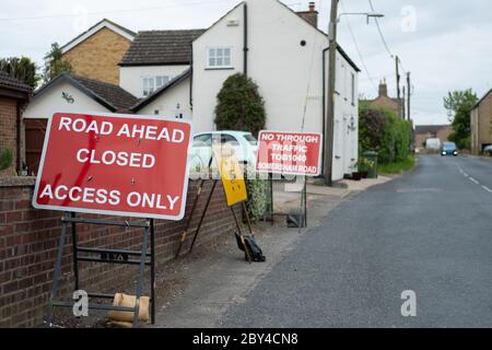 Segnali di avvertimento di traffico stradale multipli visti situati vicino a case rurali in un villaggio impostazione. Foto Stock