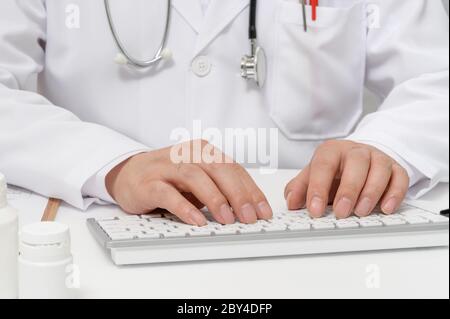 Mani di un medico maschile che utilizza una tastiera per computer. Foto Stock