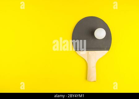 Racchetta da ping pong con palla su sfondo giallo.concept sport. Foto Stock