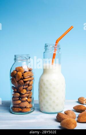 Latte di mandorle bianche biologiche in bottiglia di vetro su sfondo blu Foto Stock