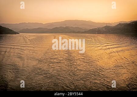 Il sole tramonta getta un'incandescenza color rame sul fiume Yangtze. Foto Stock