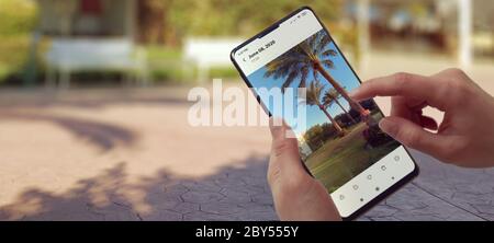 Hipster Girl Invio di foto di viaggio da smartphone, cellulare Close Up View. Mani turistiche che usano Gadget, telefono o dispositivo su sfondo sfocato prospettiva. Touch screen con dito e Travel Photo. Foto Stock