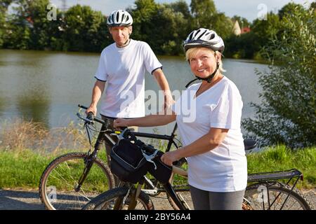 Una coppia felice di anziani va in bicicletta in estate Foto Stock