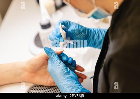 Estetista che fa la manicure, limando le unghie con un file al suo cliente in un centro di bellezza. Concetti di affari e bellezza Foto Stock