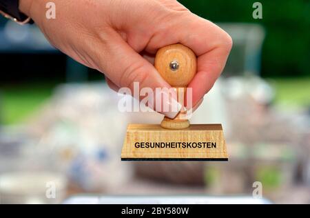 Mano con timbro scritta Gesundheitskosten, costi sanitari, Germania Foto Stock