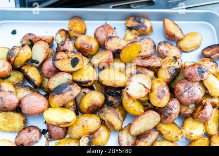 Grigliare piccole patate con fettine di aglio su una piscina grill a gas. Foto Stock