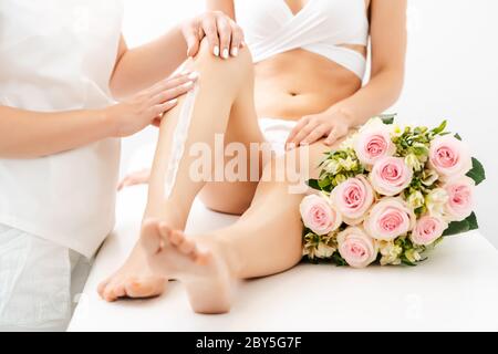 Epilazione con crema sulle gambe di bella donna in salone di bellezza Foto Stock