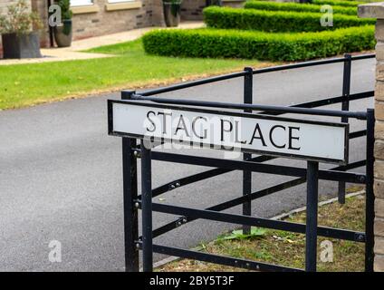 Un cartello stradale britannico per una strada chiamata Stag Place montato su pali, nero con sfondo bianco Foto Stock