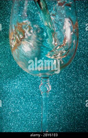 Macro Studio Shot di vino bianco beeing versato in luce blu in cristallo vetro Foto Stock