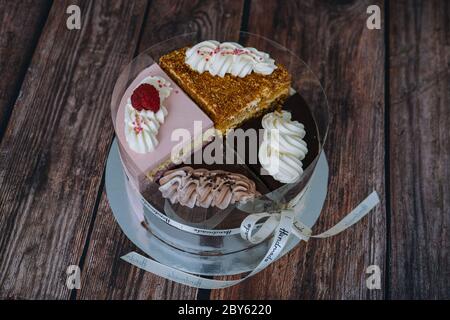 Raccolta di vari dolci su sfondo di legno. Assortimento di pezzi fette con crema. Piatto con diversi tipi di dolci. Diverse fette di deliziosi dessert. Menu pasticceria Foto Stock