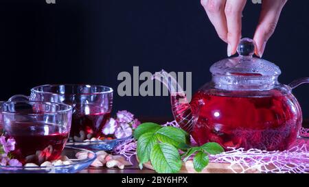 Tè rosso, ibisco, karkade, Rooibos. Una donna fa il tè. Cerimonia, tè pomeridiano, colazione. Tè, carcade. Orientale, accogliente, tradizione, giapponese, le Foto Stock