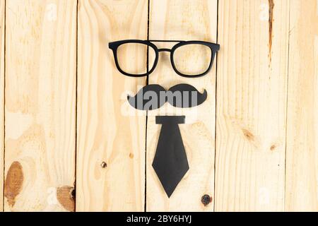 Happy Father Day concetto di sfondo con bicchieri, cravatta nera e baffi neri su sfondo di legno con spazio per la copia del testo. Foto Stock