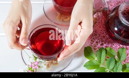 Una donna tiene una tazza di tè. Tè rosso, ibisco, karkade, Rooibos. Cerimonia, tè pomeridiano, colazione. Tè, carcade. Orientale, accogliente, tradizione, jap Foto Stock