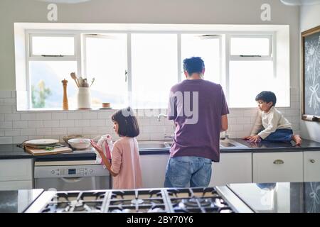La famiglia fa piatti al lavandino della cucina Foto Stock
