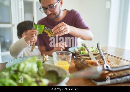 Il padre e il figlio giocoso mangiano con il dinosauro giocattolo Foto Stock