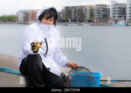 Un granchio appena catched mostrato da una donna felice asiatica Foto Stock