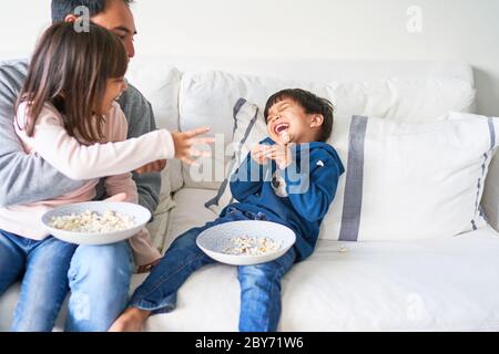 Famiglia divertente con popcorn sul divano del soggiorno Foto Stock