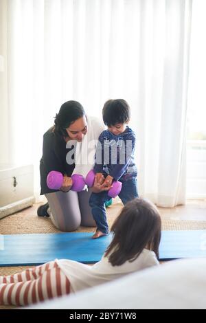 Madre e bambini che si allenano con i manubri in soggiorno Foto Stock