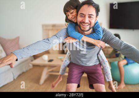 Ritratto giocoso padre piggybacking figlia Foto Stock