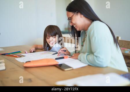 Madre aiutare mia figlia con i compiti a tavola Foto Stock