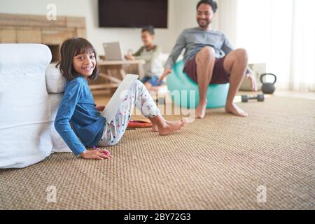 Ritratto ragazza felice facendo compiti in soggiorno con la famiglia Foto Stock