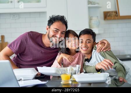 Ritratto buon padre e bambini che mangiano cibo da asporto in cucina Foto Stock